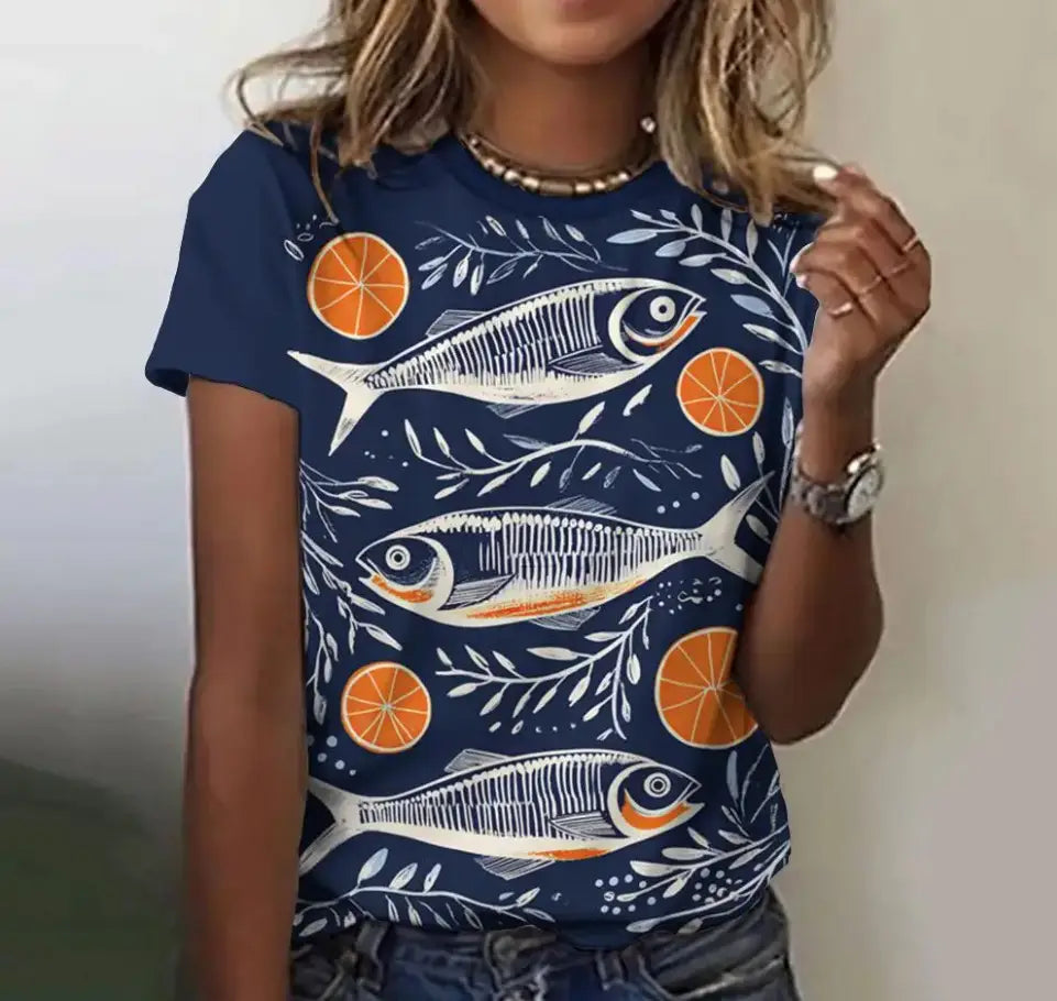Marineblaues Damen-T-Shirt mit kurzem Ärmel und grafischem Motiv, mit einem weißen und orangefarbenen Fisch- sowie Orangenscheiben-Muster und blattartigen Akzenten im Retro-Casual-Stil.