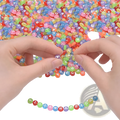 A pair of hands threading colorful translucent acrylic alphabet and number beads from an 800 piece mixed set
