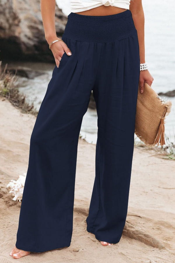 Navy blue high waist smocked wide leg pants for women featuring a stretchy elastic waistband and side pockets.