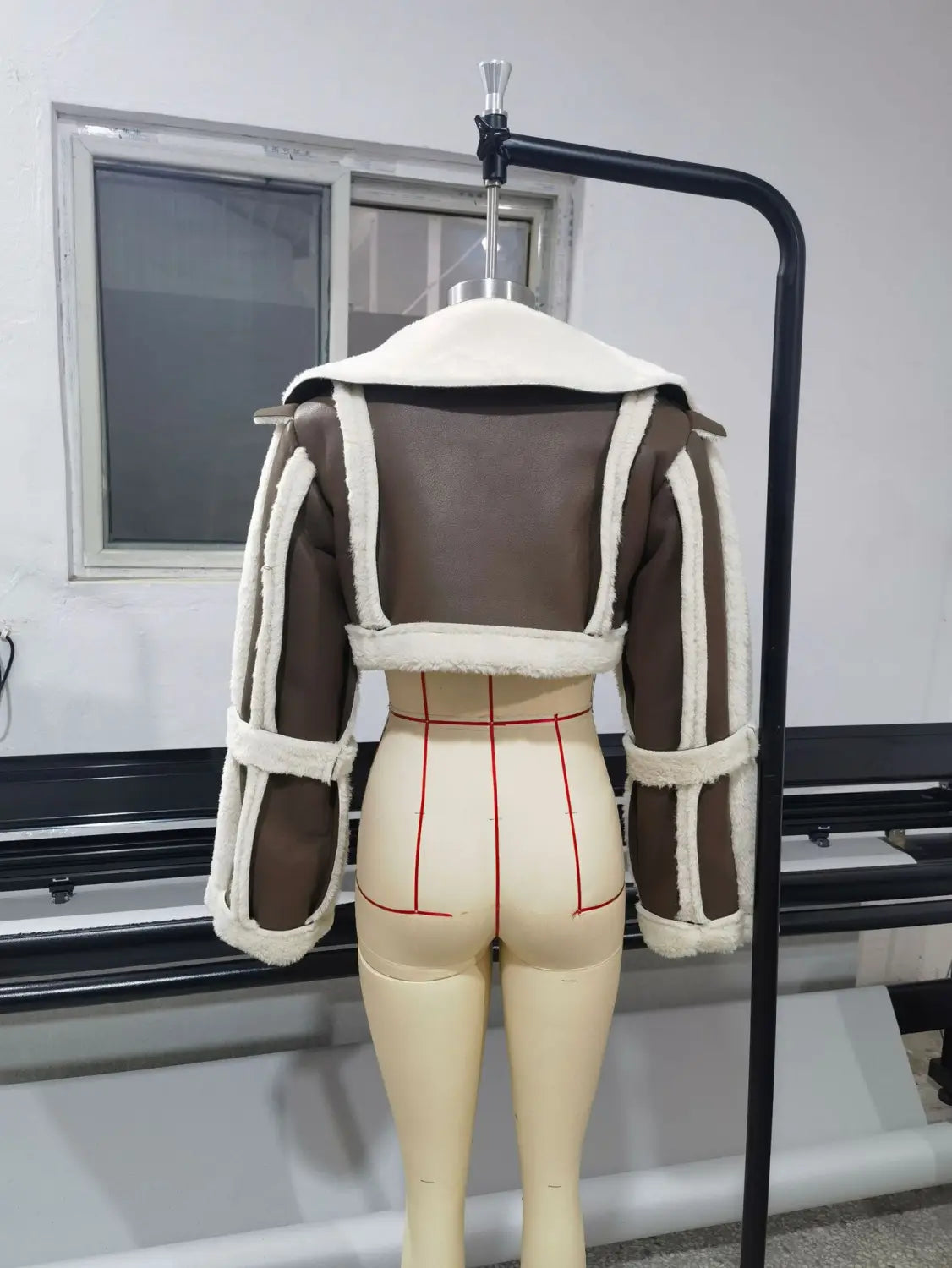 Shearling leather short jacket for women in brown with cream-colored fleece lining and trim displayed on a mannequin.