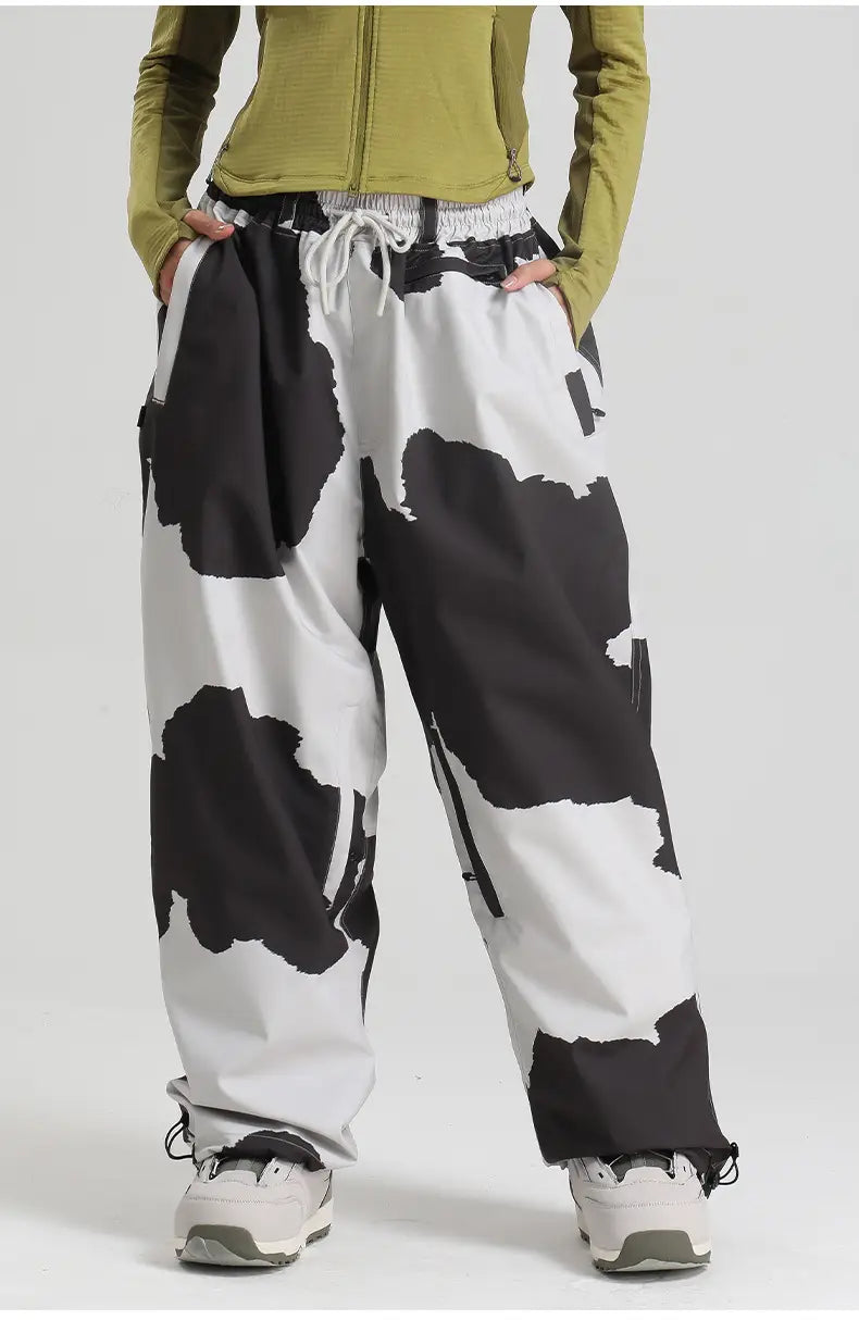 Waterproof windproof snow pants featuring black and white cow print with a drawstring waistband for a loose fit suitable for work and outdoor activities.