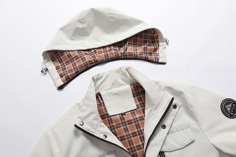 Herren-Wasserabweisender Trenchcoat mit Kapuze in Weiß mit Kapuze, mit karierter Innenausstattung in Orange- und Brauntönen sowie schwarzem Zierband entlang der Kanten.