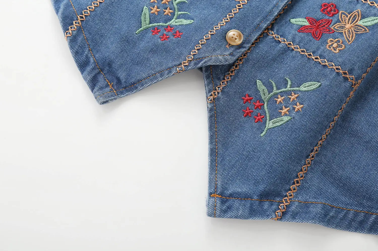 Bestickte florale Jeansweste mit einer blauen Jeansjacke mit farbenfroher floraler Stickerei und einem einzelnen braunen Knopf.