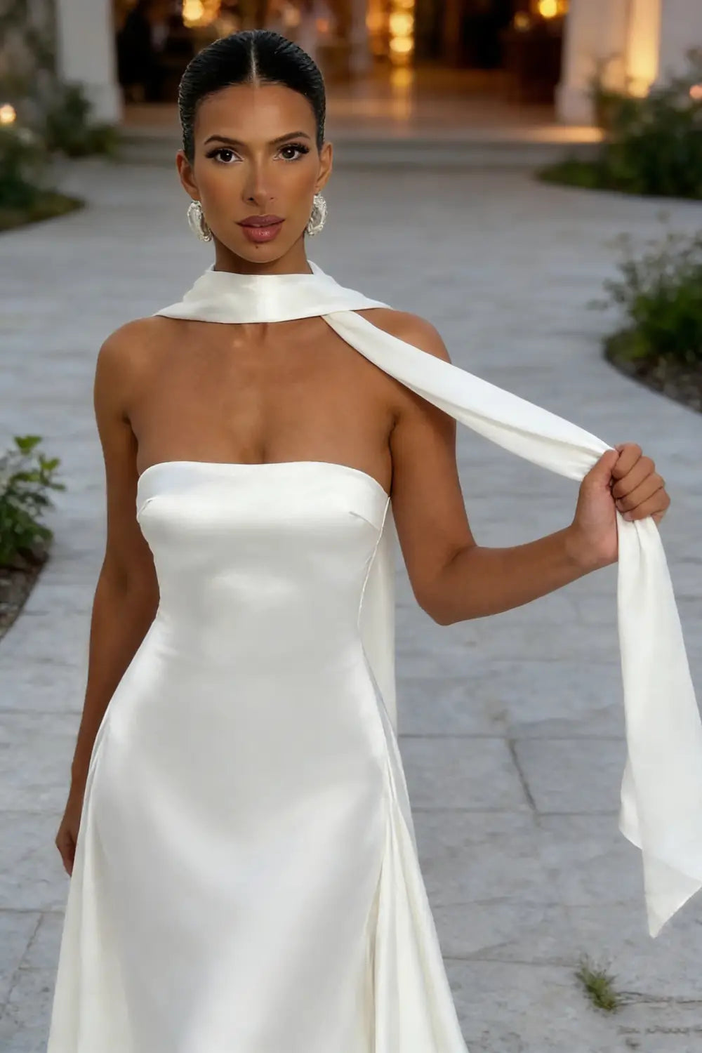 Vestido de noche elegante sin tirantes de satén blanco, con un diseño pulcro y un detalle de cinta fluida en el escote.