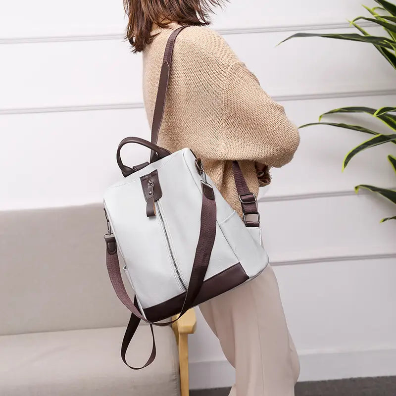 Eleganter Rucksack mit Diebstahlschutz aus weißem und braunem Leder mit verstellbaren Trägern, entworfen für Reisen in der Stadt.