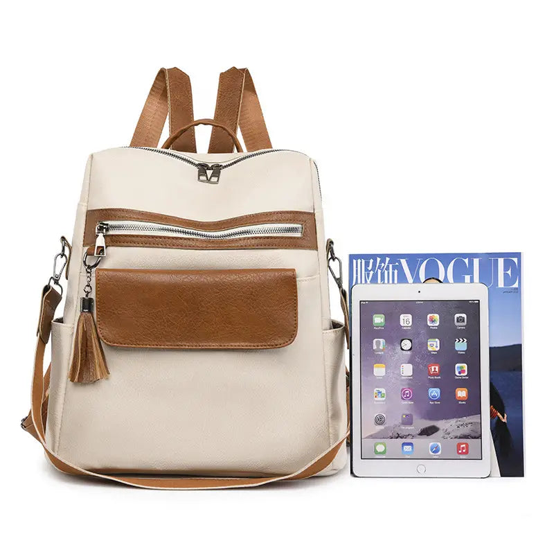 One shoulder cream faux leather backpack with brown leather accents zipper details and tassel charm measuring 35cm.