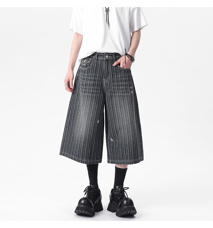 Striped denim capri shorts feature black and white vertical stripes with a distressed wide-leg cut.