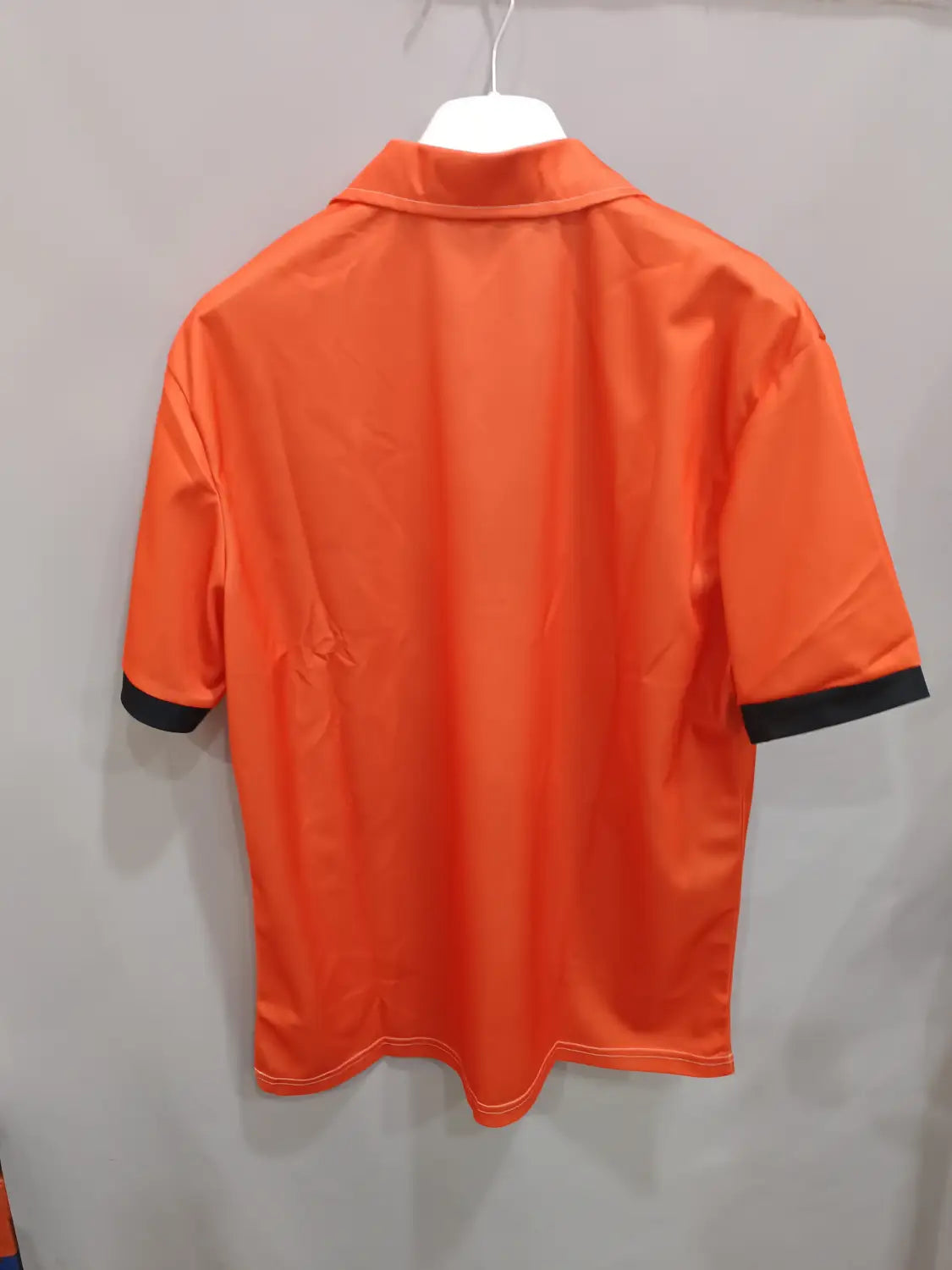 Leuchtend orangefarbenes Kontrast-Herren-Poloshirt mit schwarzem Besatz an Kragen und Ärmelmanschetten, aus atmungsaktivem Stoff, für den Freizeitgebrauch.