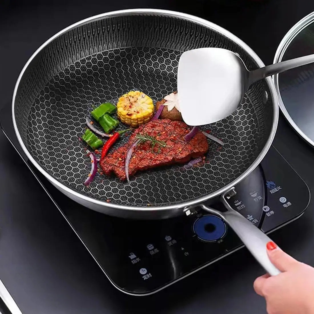 Black hexagonal-patterned nonstick 30cm stainless steel induction frying pan with stainless steel rim and handle on an induction cooktop.