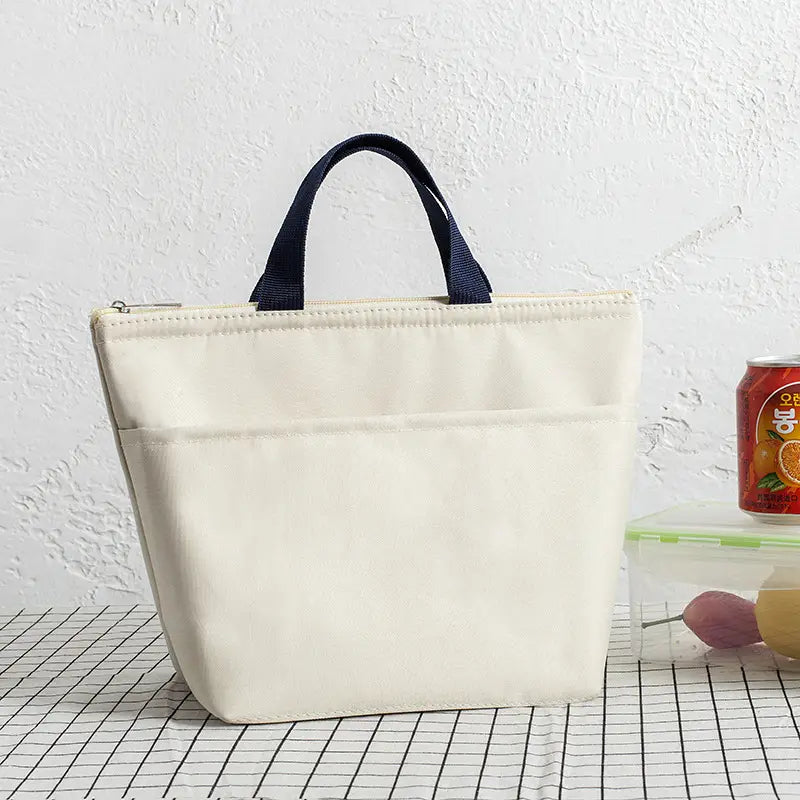 Hellcremefarbene isolierte Oxford-Bento-Lunchbag mit dunkelblauen Stoffgriffen und Reißverschlussverschluss, aus Canvas gefertigt.