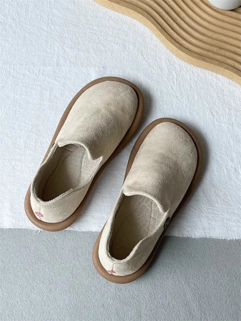 Beige Veloursleder-Slipper im Vintage-British-Stil mit niedrigem Absatz mit einer massiven braunen Gummisohle.