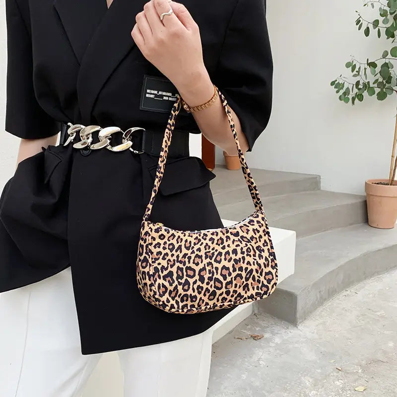 Animal print underarm shoulder bag for women featuring a leopard-print pattern with a curved soft body and matching strap.
