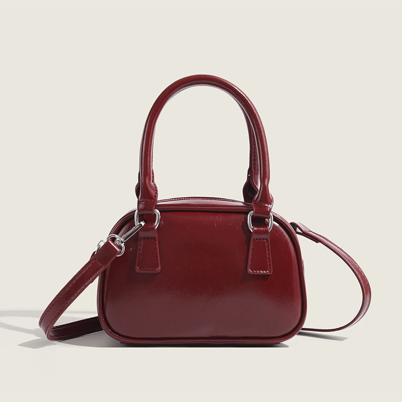 A glossy burgundy pu leather small square handbag with rounded top handles and a detachable shoulder strap measuring 20cm.