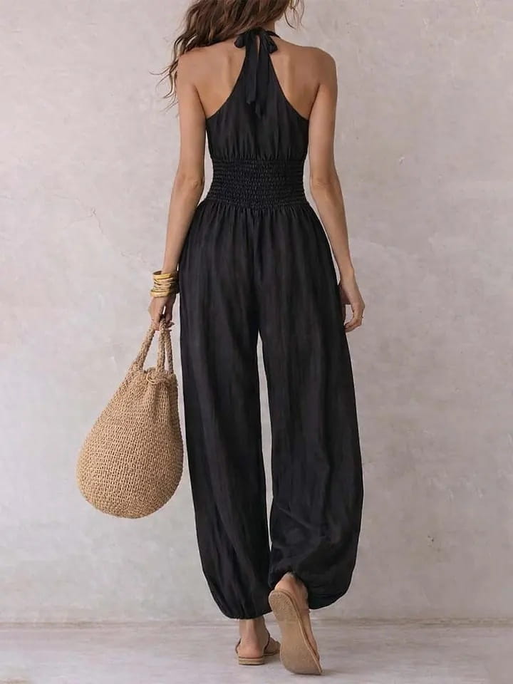 Mono tipo halter de pierna ancha en color negro con cintura fruncida y pantalones sueltos que caen con fluidez en una tela ligera, adecuada para ocasiones elegantes y casuales