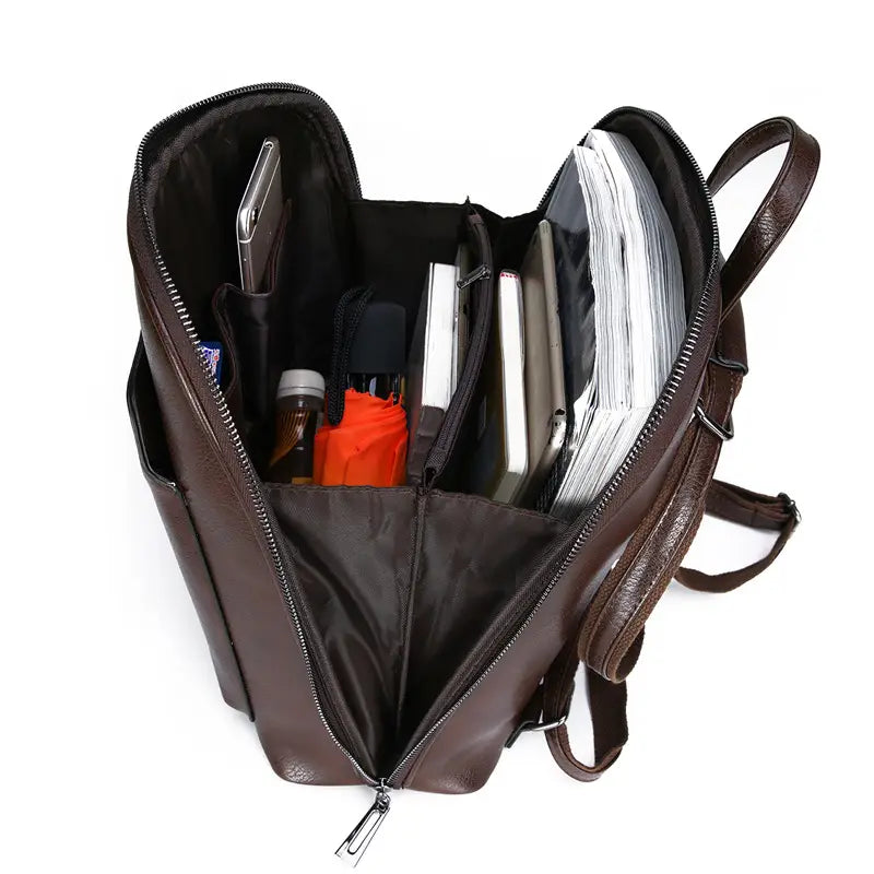brown pu leather anti-theft backpack with magazine print featuring multiple compartments and zippers filled with books phone an umbrella and other items
