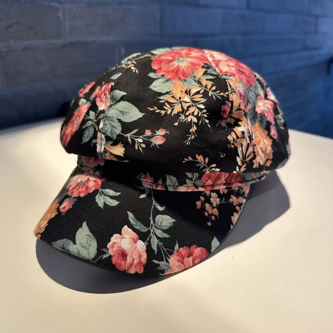 Floral newsboy cap for women featuring black fabric with vibrant pink and orange rose patterns against a dark background.