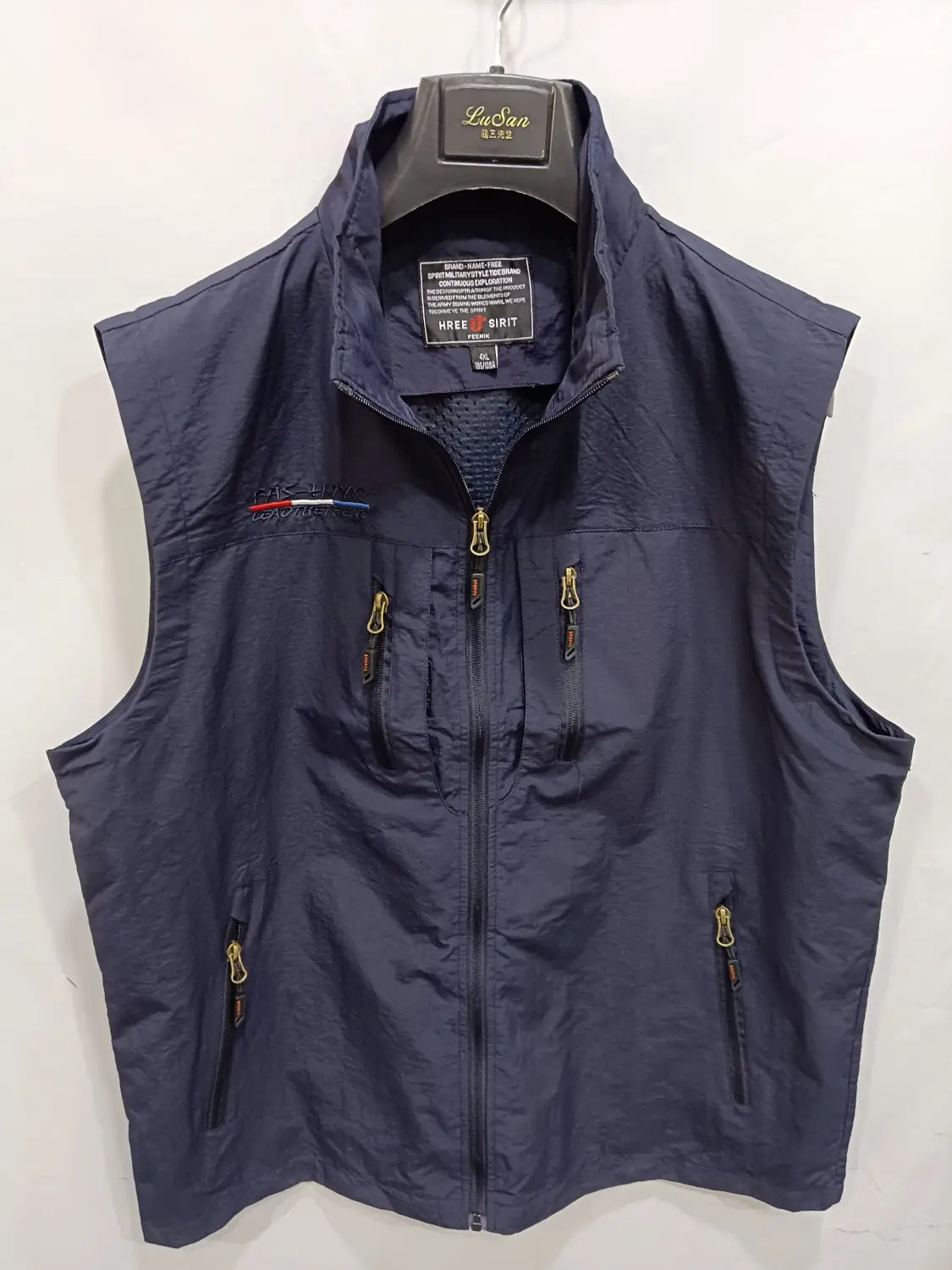 Chaleco utilitario con capucha y múltiples bolsillos para hombre en tejido lusan azul marino oscuro, diseño sin mangas, cremalleras tono dorado y un logotipo bordado sutil de lusan en el lado izquierdo del pecho.
