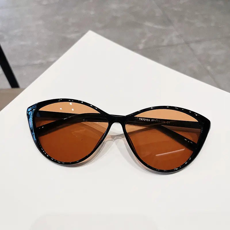 Lunettes de soleil œil-de-chat noires UV380 légères pour la mode, avec des verres teintés ambrés, conçues pour la protection solaire et le style.