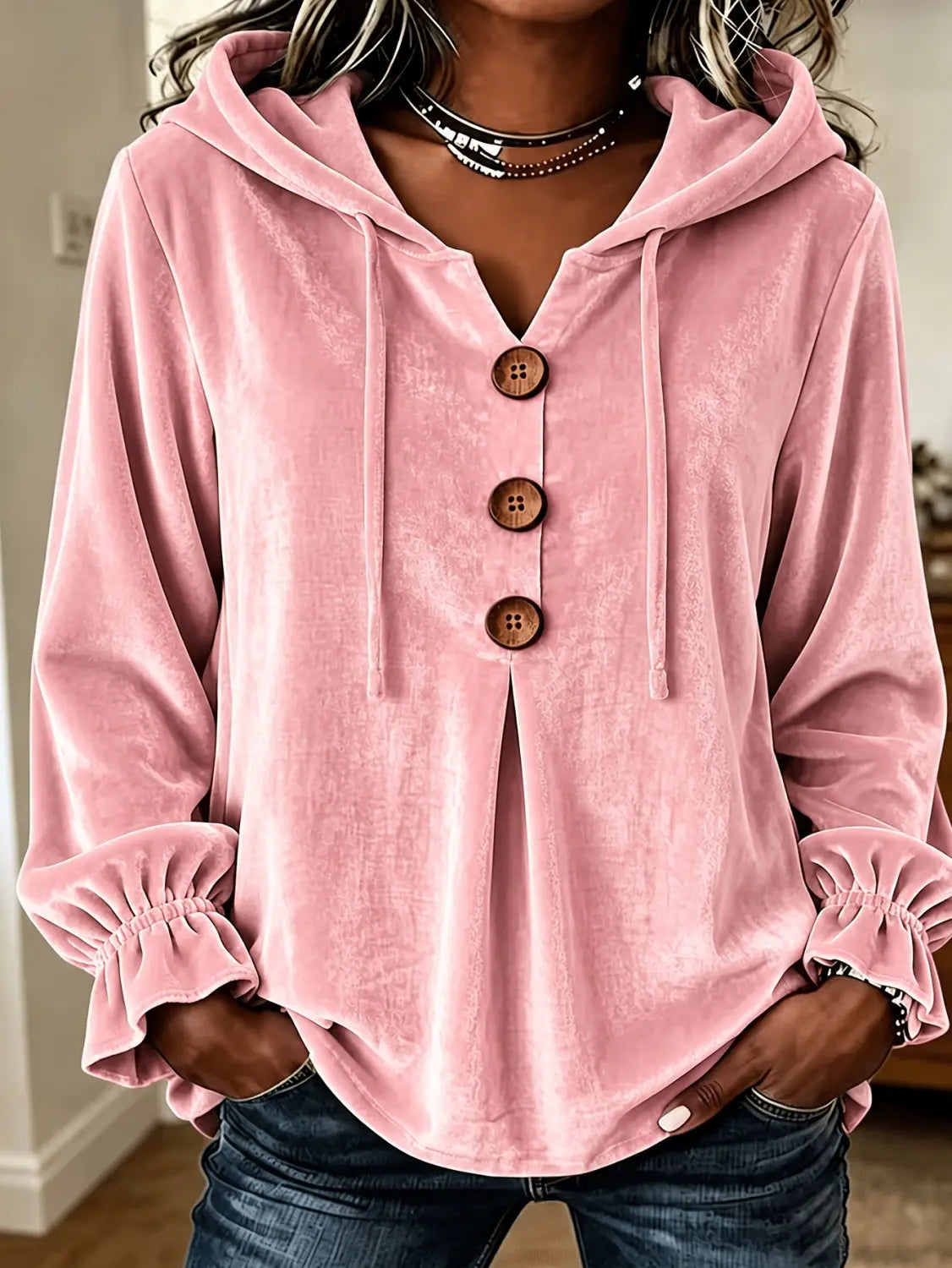 Sudadera de terciopelo rosa con botones de madera y puños fruncidos, exhibida de frente.