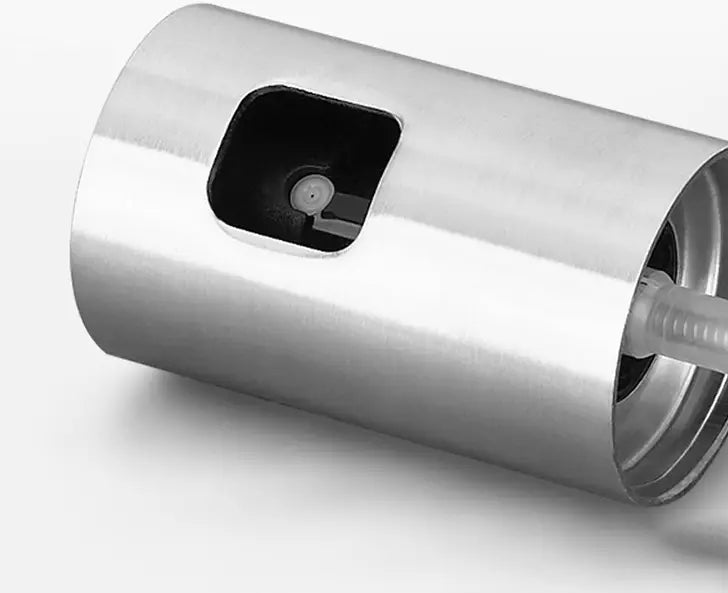 Zylindrischer Spender aus Edelstahl für Handdesinfektionsmittel mit einer eleganten reflektierenden Oberfläche und einer quadratisch geformten Pumpenöffnung, gezeigt als Rückseite einer auslaufsicheren Glassprühflasche für Kochzwecke.