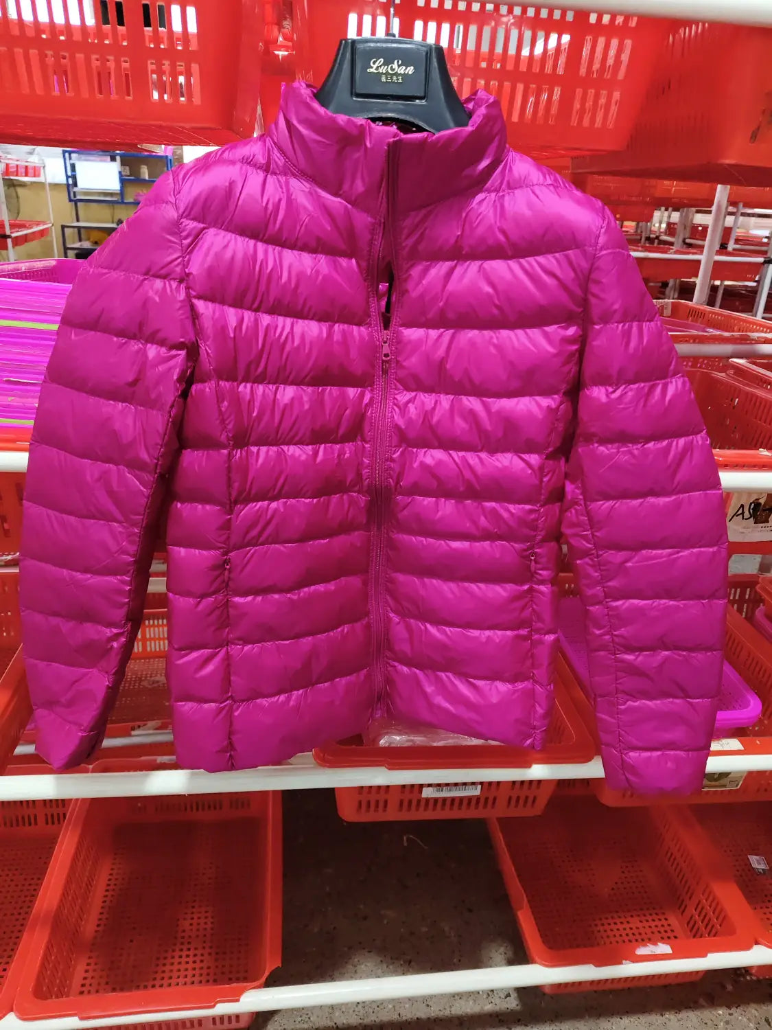 Eine kräftige Fuchsiafarbene Slim-Down-Jacke mit Steppdesign und Stehkragen, die auf einem schwarzen Bügel präsentiert wird.