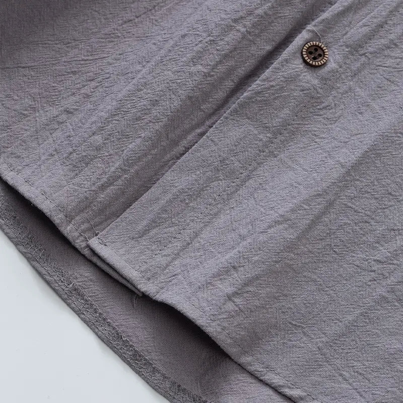 Men’s gray linen blend sleeveless hooded button up shirt with textured slightly wrinkled fabric and rustic wooden button.