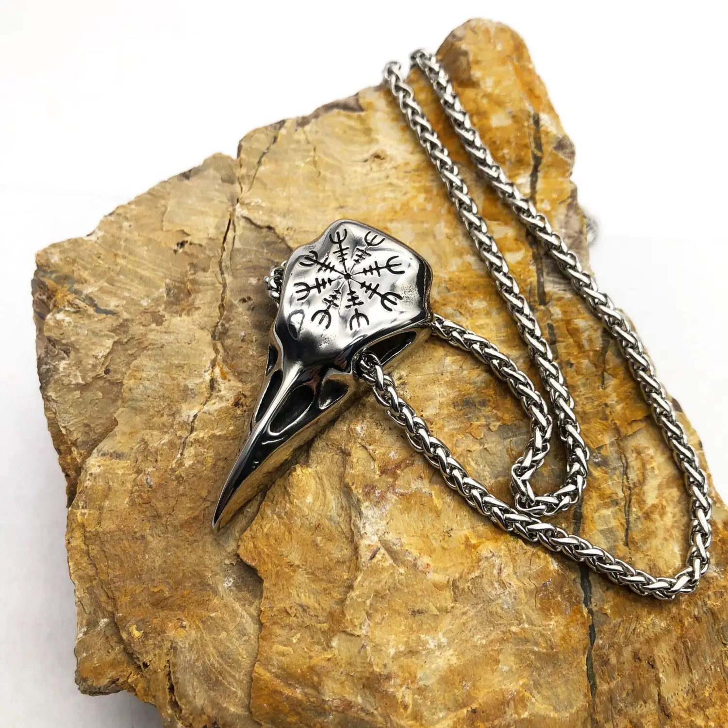 Silver vintage Viking runic raven skull pendant on a braided stainless steel chain necklace.