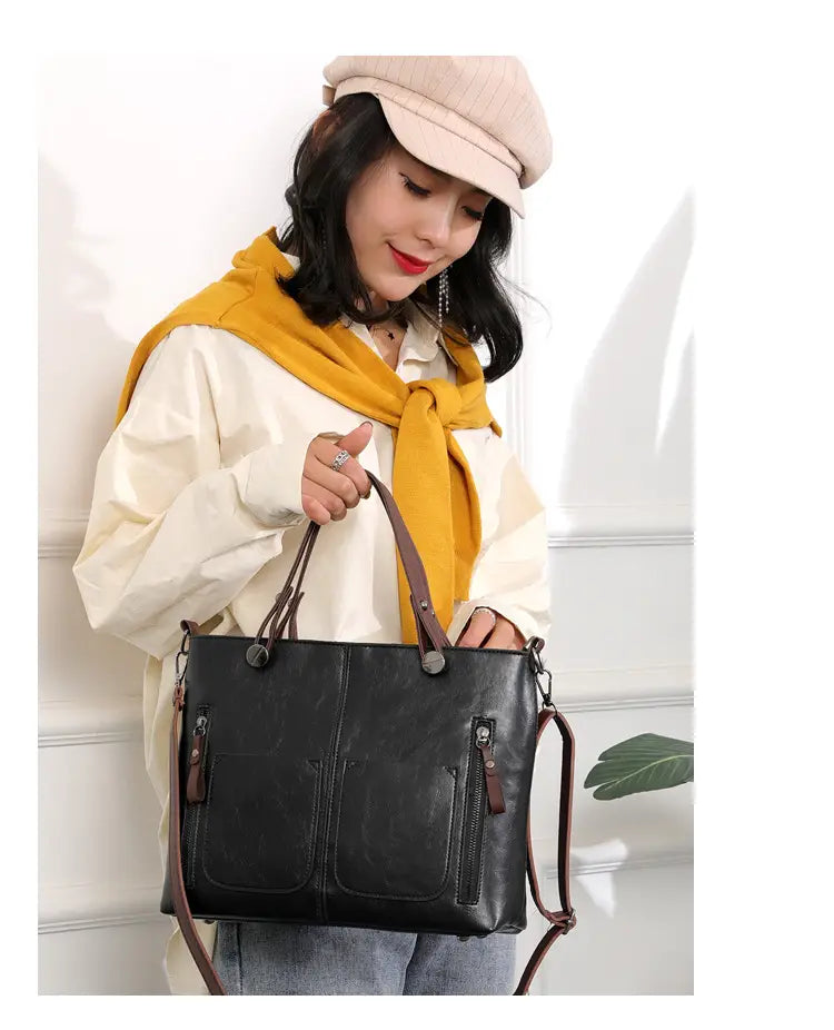 Black leather tote bag with brown straps and zippers featuring a retro large capacity design ideal for crossbody use.