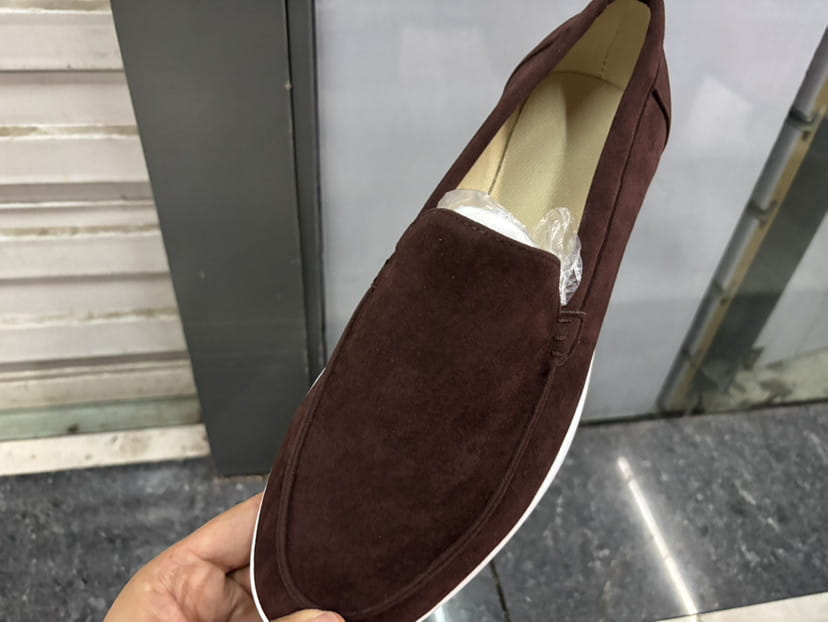 Mocasines de ante marrón para hombre, tipo slip-on, con suela de goma blanca, calzado casual, mostrados desde el frente.