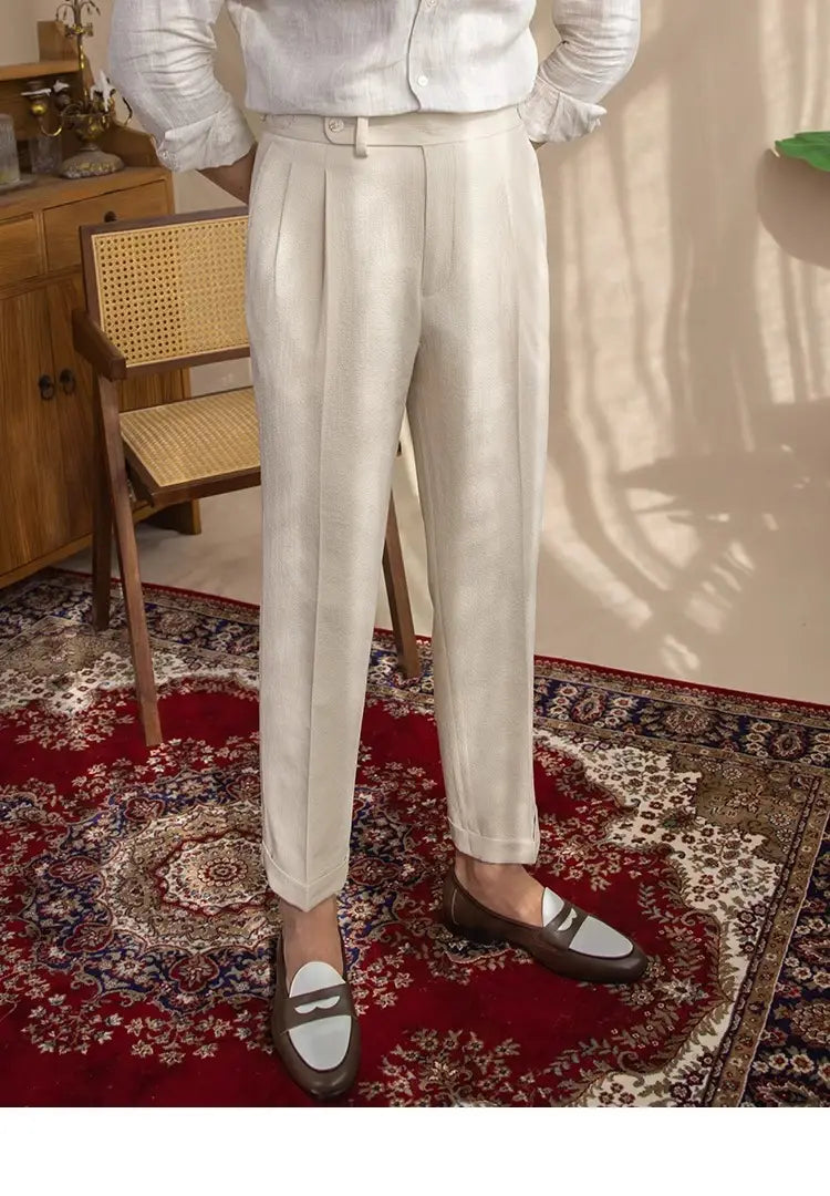 Cream-colored men’s slim fit pleated summer linen suit trousers with tailored fit and rolled cuffs.