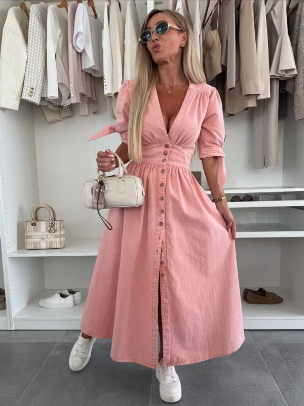 A soft pink button front midi dress with puffed sleeves and a v-neckline made from denim material.