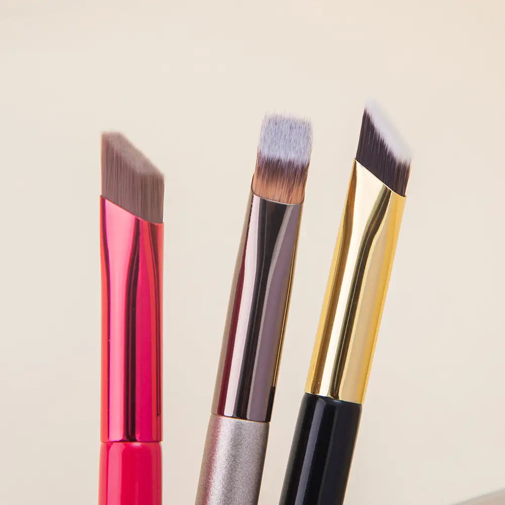 three angled wild eyebrow brushes with metallic handles in pink silver and gold finishes designed as 3d stereoscopic makeup tools