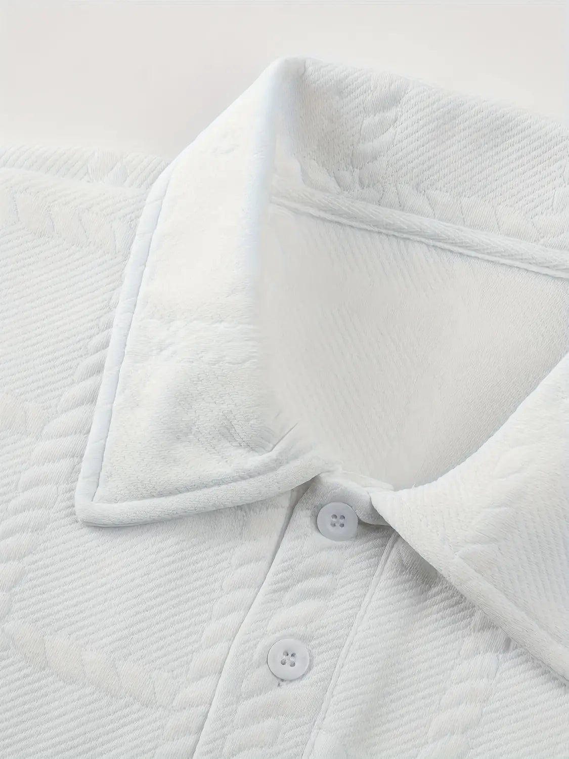 Camisa tipo polo de manga larga blanca con textura, confeccionada con algodón acolchado, con un cuello texturizado suave y botones a juego.