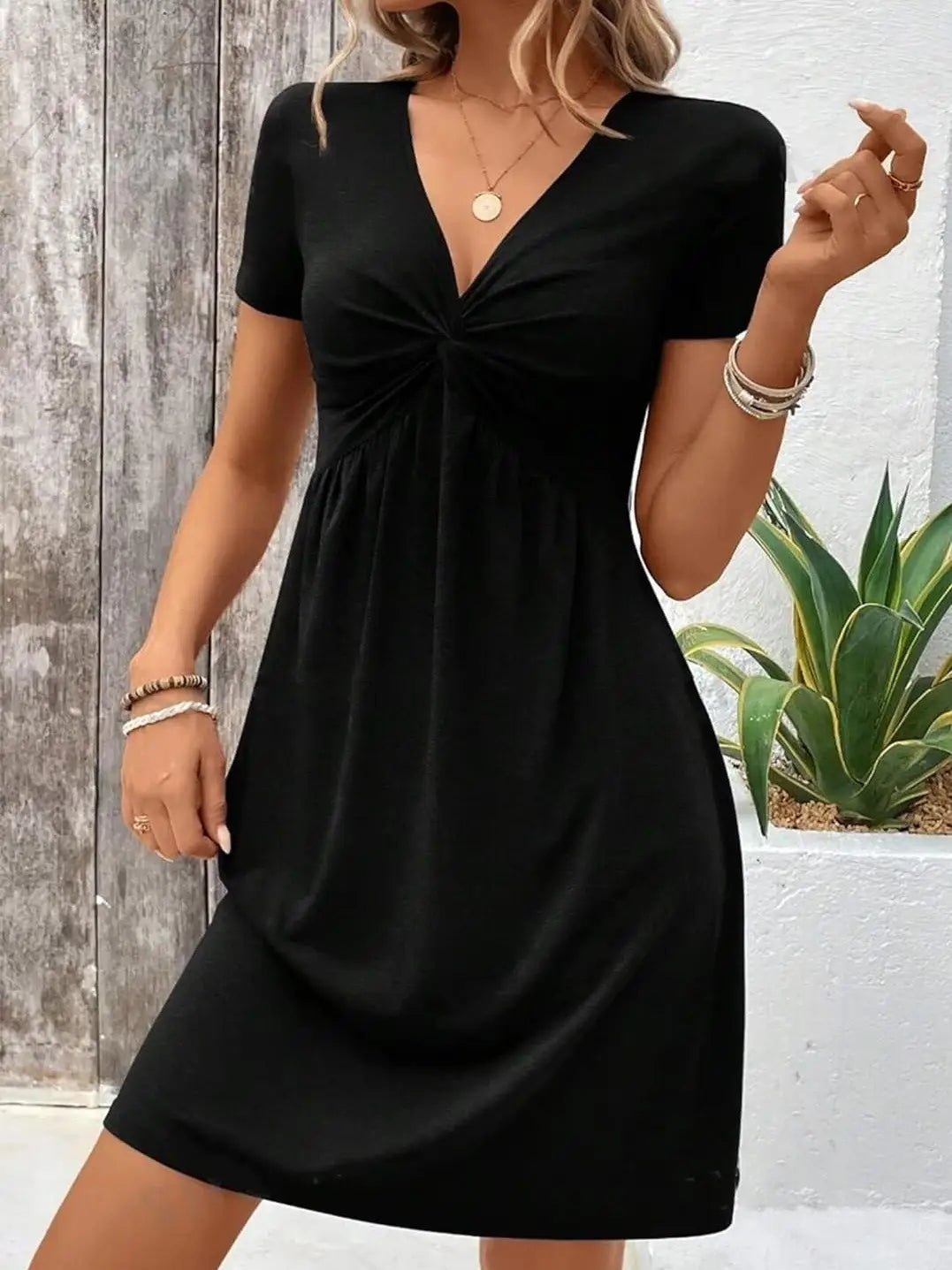 Black short-sleeved midi dress with a v-neck and knotted front detail made from soft fabric for elegant occasions.