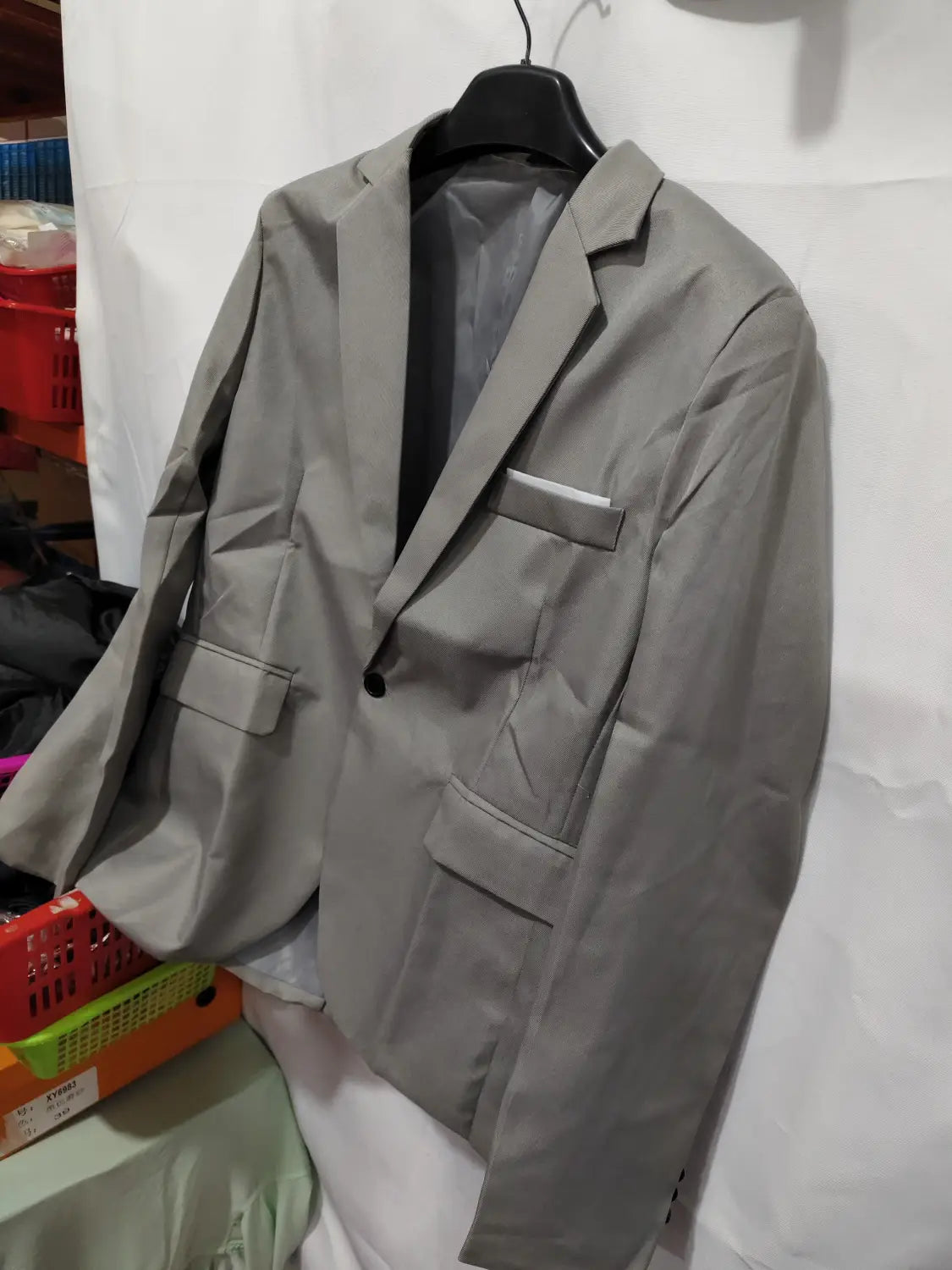 Herren-Slim-Fit-Fuchsia-Freizeitblazer in Grau mit einem einzelnen schwarzen Knopf und zwei Patten-Brusttaschen, hängend an einem schwarzen Bügel.
