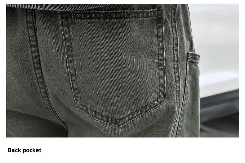 The back side of olive green cargo pants for men in cotton workwear features a dark gray denim back pocket with reinforced stitching and a classic rectangular shape.