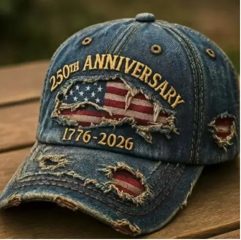 Distressed blue denim baseball cap featuring a torn American flag patch with 250th anniversary 1776-2026 embroidered in gold thread.