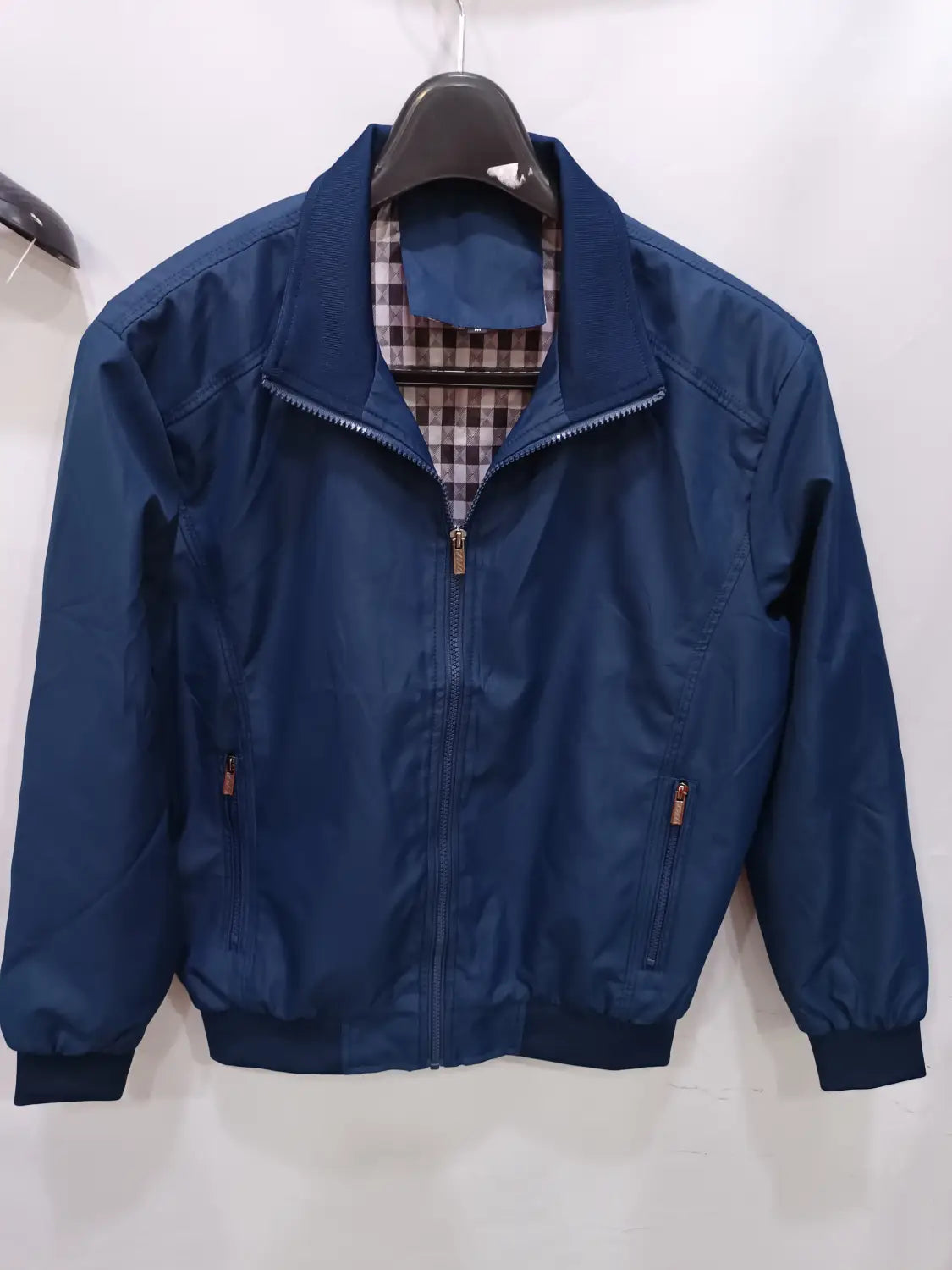 Veste bombardier légère pour homme en nylon bleu marine, avec fermeture éclair et doublure intérieure à carreaux, présentée depuis l’arrière.