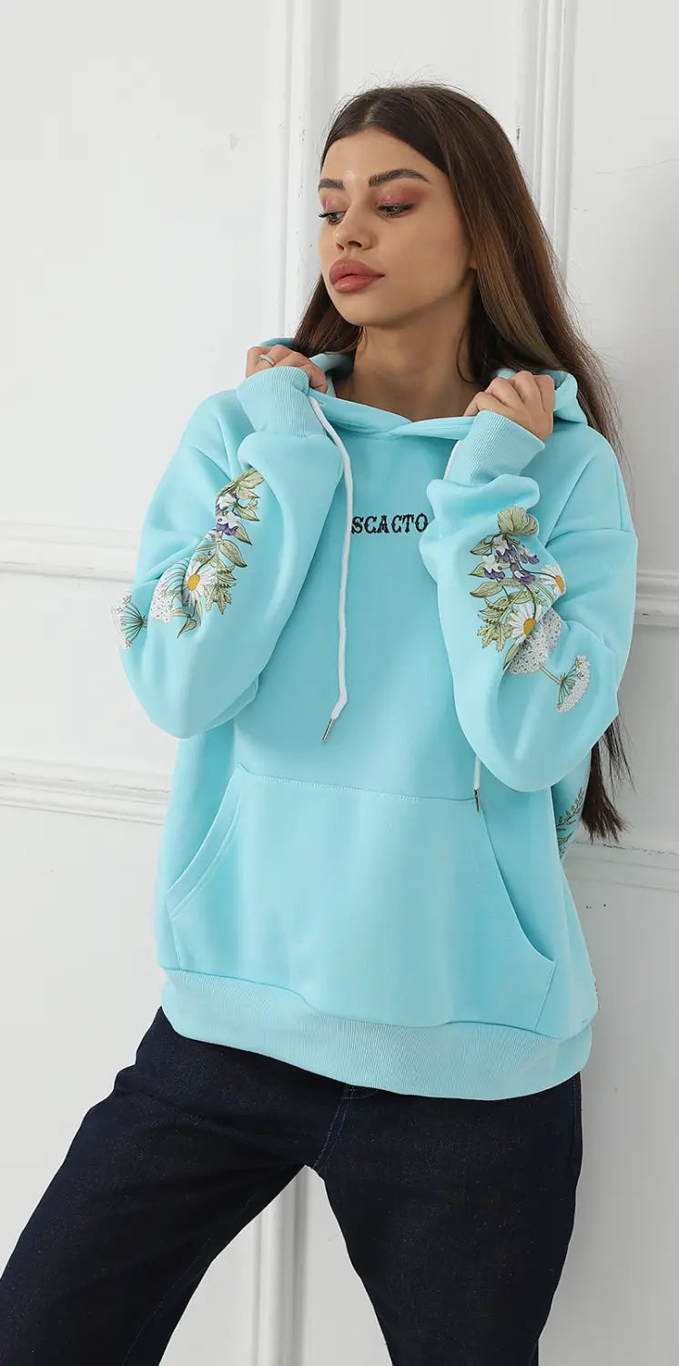Light blue women’s long sleeve hoodie with floral embroidery on the sleeves and a black scacto logo across the chest.