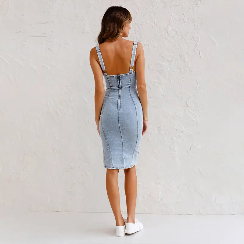 light-wash denim midi dress with thin straps and back zipper shown from the back featuring a slim fit square neck and side slit