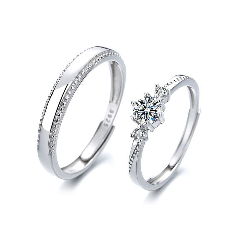 A pair of elegant silver sterling silver couple rings titled Love at First Sight featuring one ring with a central diamond surrounded by smaller diamonds and the other with a delicate beaded edge.