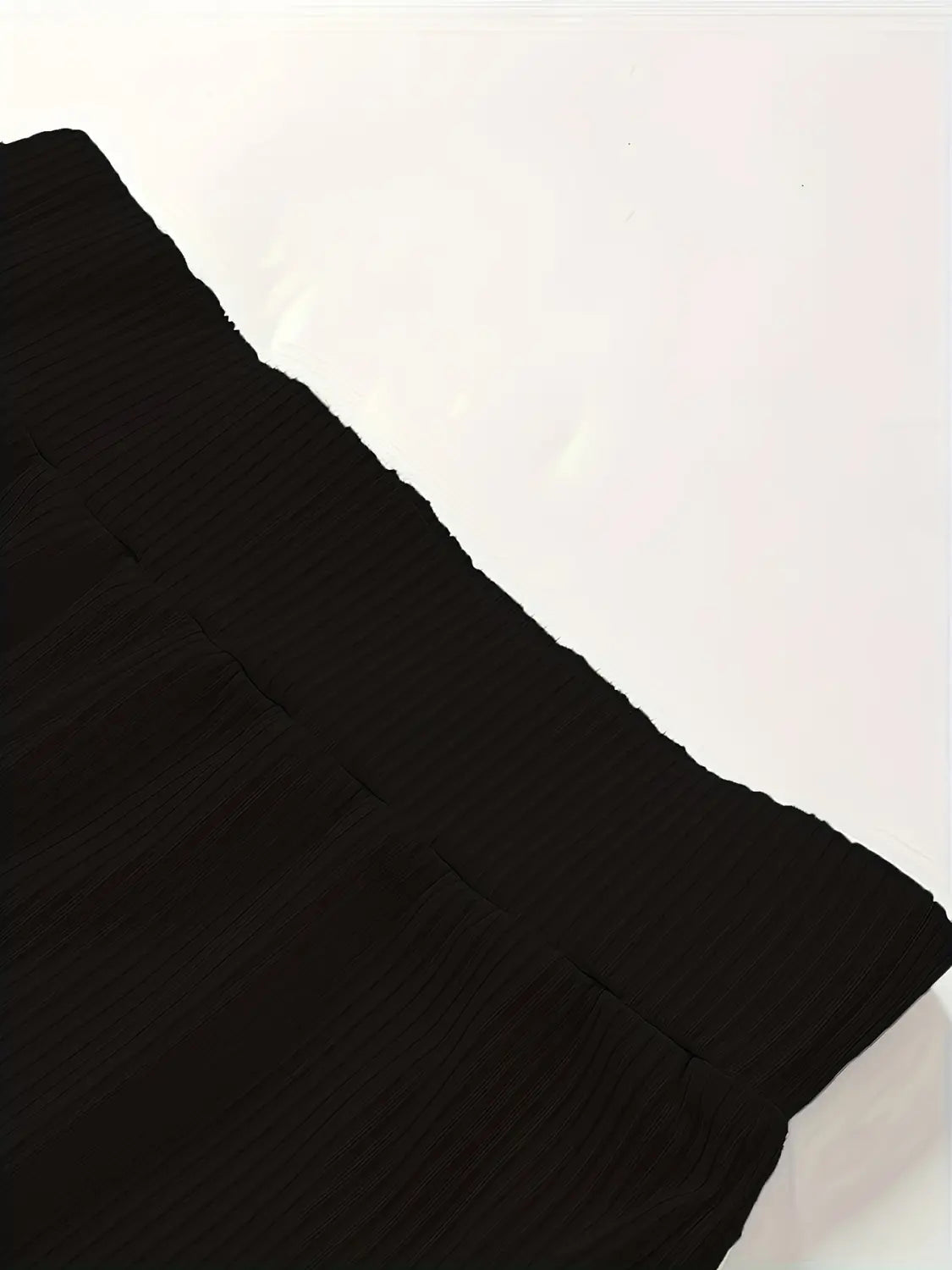 Schwarzer Strickstoff mit Rippenstruktur und glatter, leicht strukturierter Oberfläche, verwendet für hoch geschnittene Ripp-Flared-Leggings.