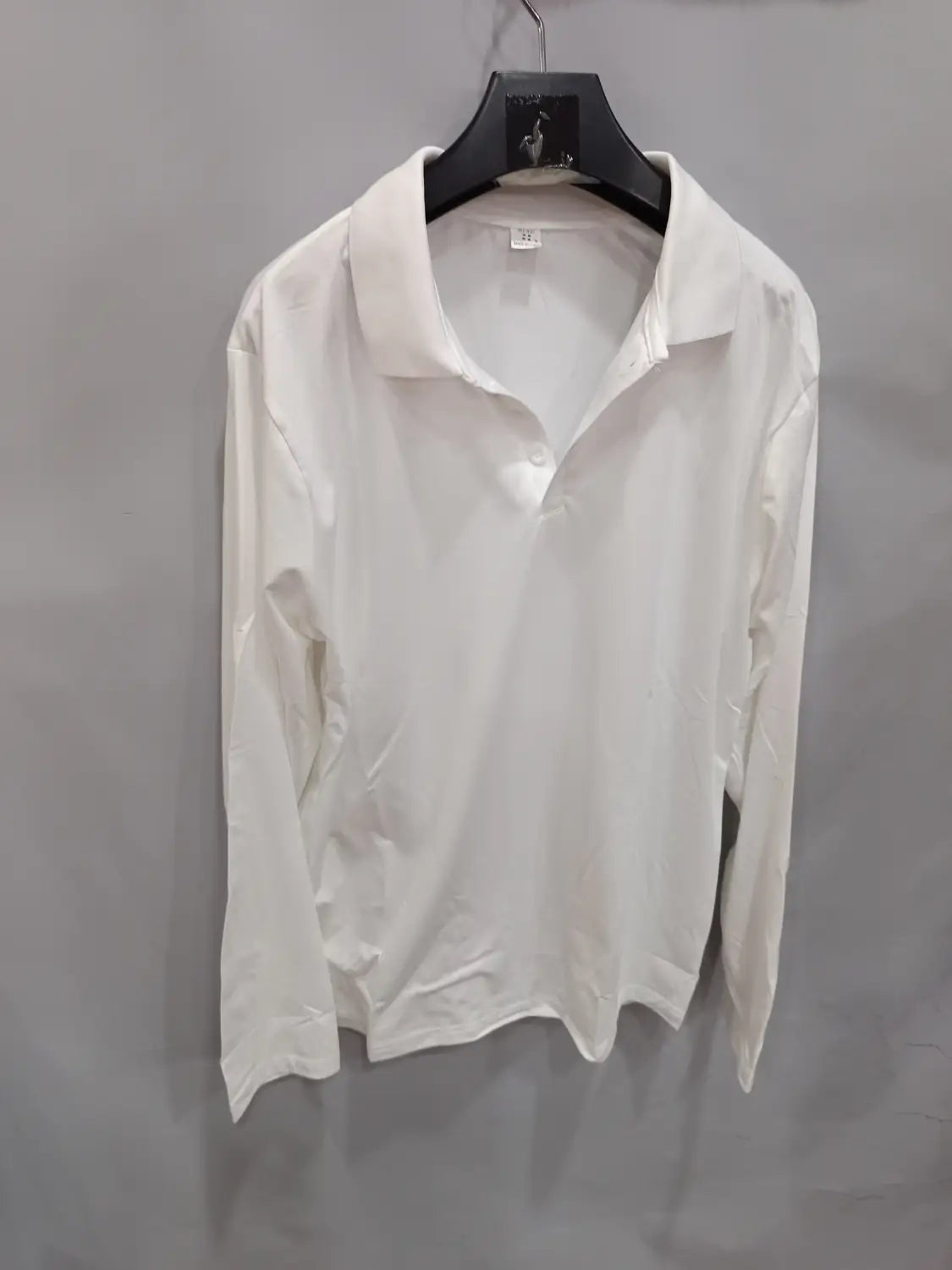 Weißes langärmliges Polohemd mit klassischem Kragen und geknöpfter Knopfleiste, an einem schwarzen Kleiderbügel hängend, geeignet für den Casual-Sportgebrauch.