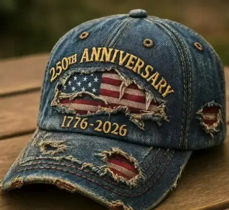 A distressed blue denim baseball cap featuring a torn American flag patch embroidered with 250th anniversary 1776-2026 in gold thread for America 250th anniversary.