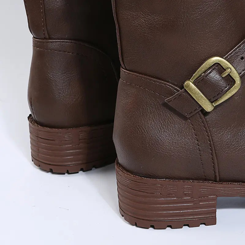 Leather knee high knight boots in brown leather with a brass buckle strap and textured rubber soles.