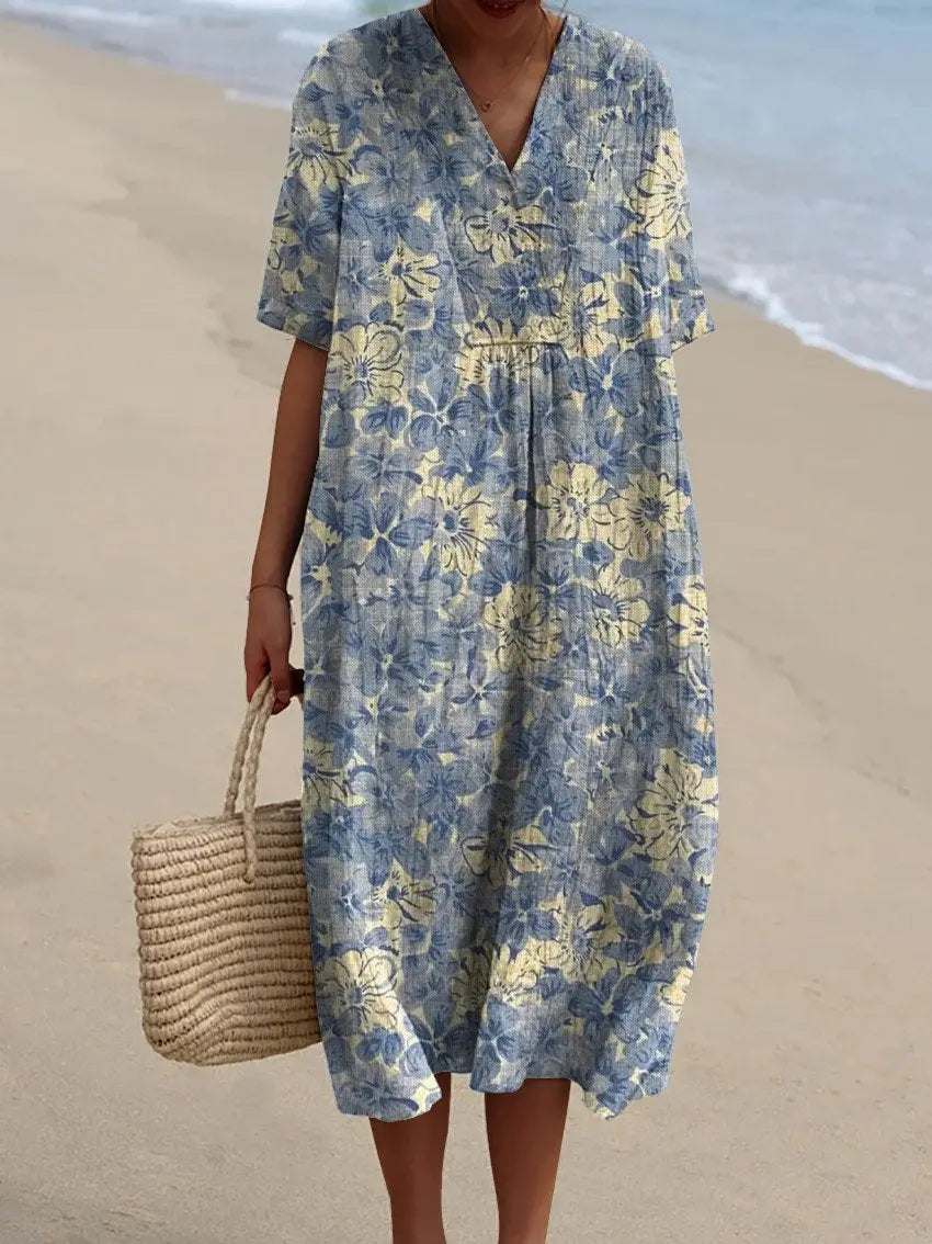 A flowing blue and yellow floral print maxi dress with a v-neckline short sleeves and a gathered waist.