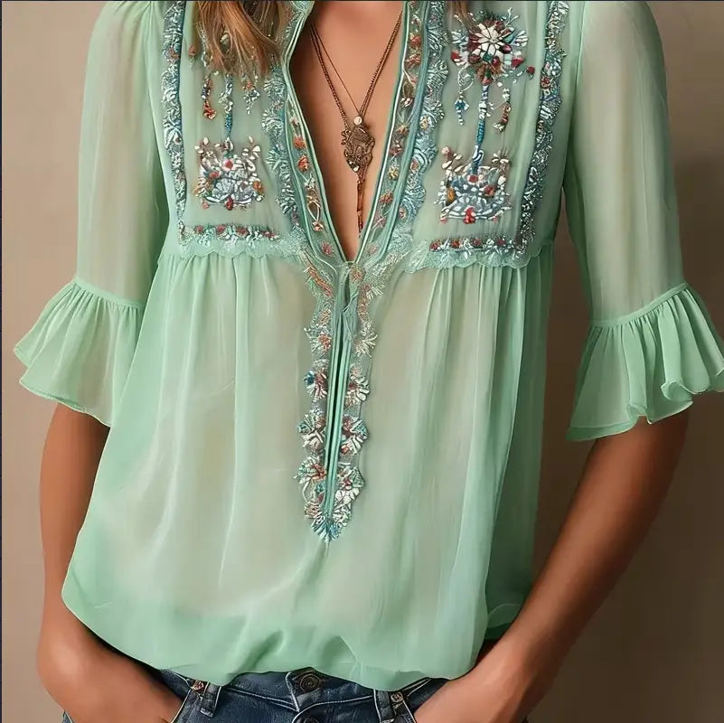 Blouse en mousseline de soie brodée vert menthe, présentant une broderie florale complexe et des manches à volants.