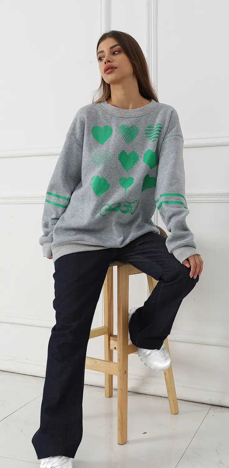 Gray oversized sweatshirt featuring green heart patterns and striped cuffs suitable for casual wear