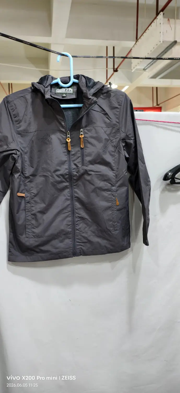 Chaqueta de senderismo con capucha impermeable color gris oscuro, con tiradores de cremallera marrón y una marca sutil en el cuello.