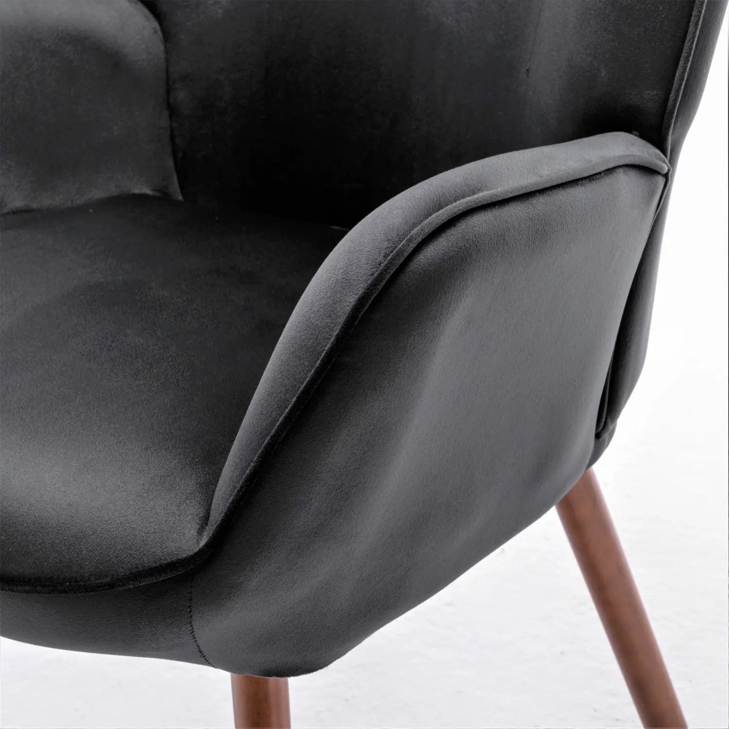 Silla de acento tipo wingback con terciopelo negro acolchado y con botones, con patas de madera, que muestra la vista frontal y un tapizado acolchado y confortable.
